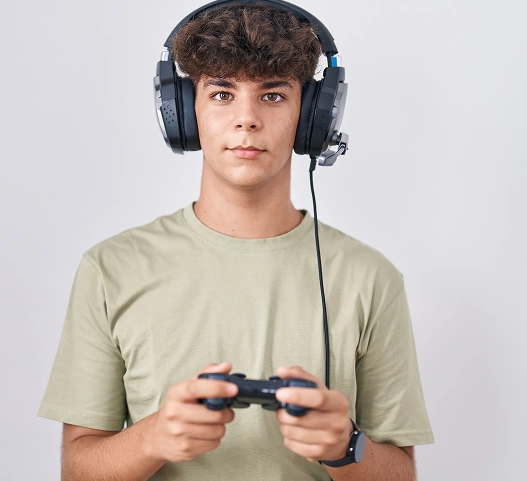 Jovem jogador a usar um auricular e a segurar um comando de videojogo enquanto olha para a câmara