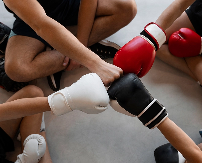 Grupo de atletas a usar luvas de boxe a juntar os punhos antes do treino ou competição